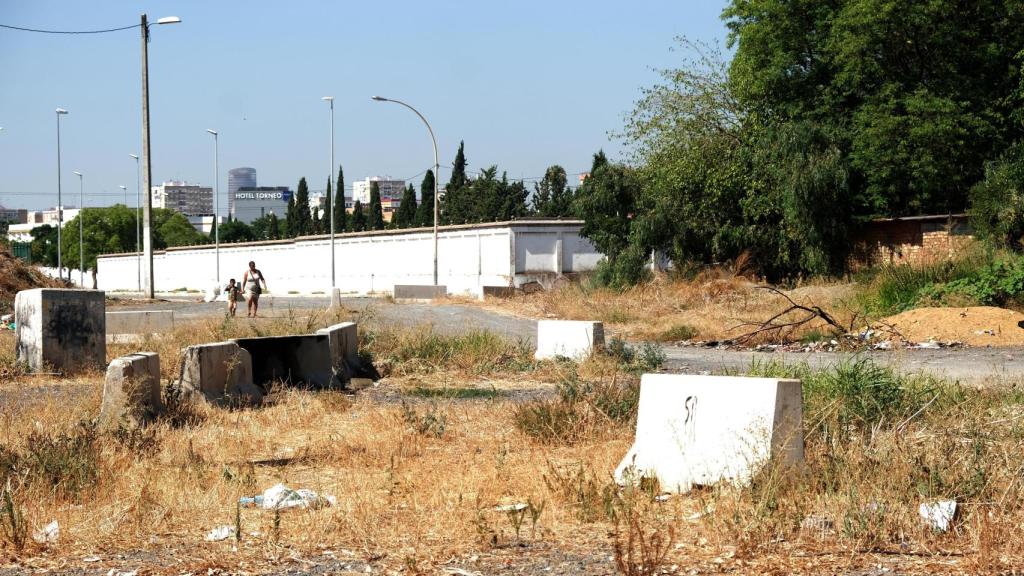 Una mujer y un niño caminan hacia El Vacie por el muro del cementerio. Justo detrás se ve la Torre Pelli y un hotel de lujo en la calle Torneo.