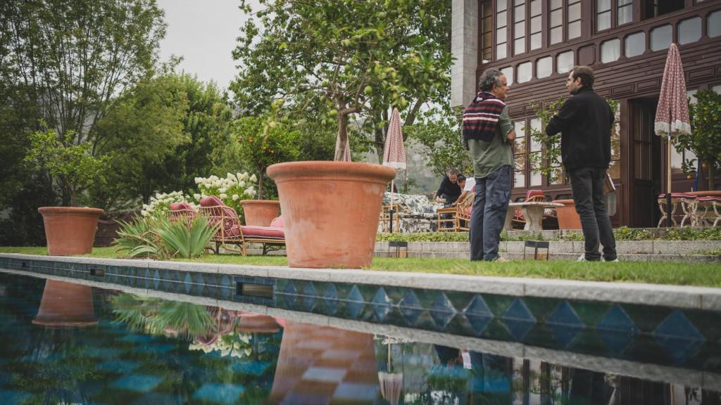 Lorenzo Castillo (i) durante la entrevista con EL ESPAÑOL; en la imagen, la fachada de su casa de estilo Tudor y neogótico de estilo inglés y parte de su mobiliario de terraza. Las telas de los asientos, por ejemplo, las diseña él.