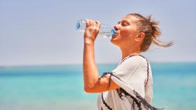 Una mujer bebe agua en la playa