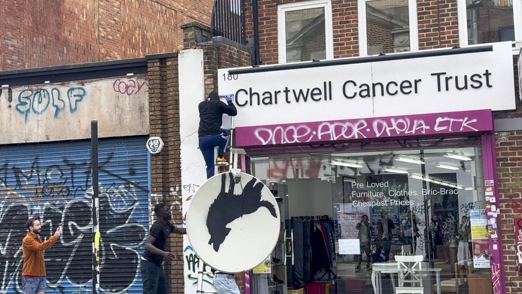 Un individuo roba la antena parabólica donde Banksy había pintado un lobo aullando, este jueves en el barrio de Peckham, Londres. Foto: Raúl Bobé/EFE