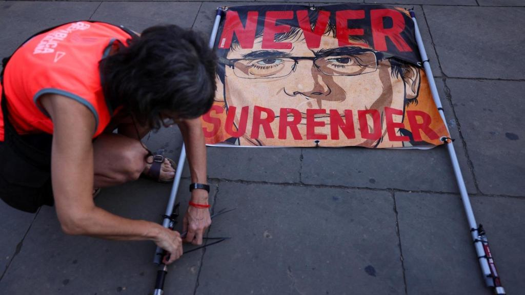 Un seguidor de Puigdemont arma una pancarta con el lema Rendirse nunca, este jueves, en las calles de Barcelona.