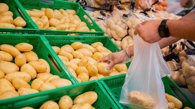 Una persona compra patatas en un supermercado.