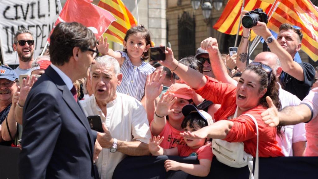 Salvador Illa saluda al público congregado ante el Palau de la Generalitat, entre banderolas del PSC y esteladas independentistas, este sábado tras prometer el cargo.