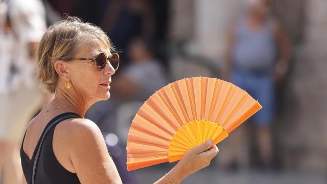 Una mujer trata de refrescarse usando un abanico en el centro de Valencia