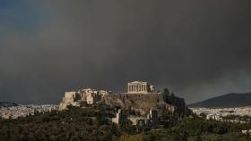 El templo del Partenón en la cima de la colina de la Acrópolis mientras se ve el humo de un incendio forestal, en Atenas.