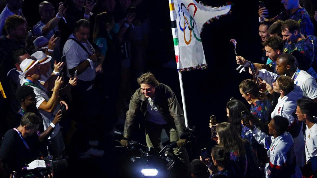 Tom Cruise sale del Stade de France en moto con la bandera olímpica.