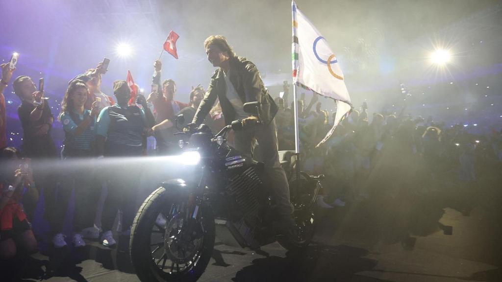 Tom Cruise se sube a la moto eléctrica de Harley-Davidson para llevar la bandera olímpica.