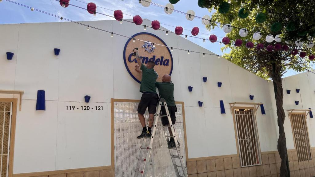 Trabajadores colocando el cartel de una caseta