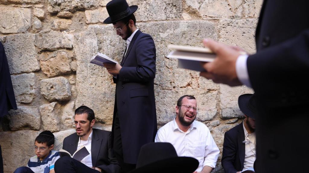 Judíos ortodoxos rezan mientras leen el libro de Eicha (Libro de las Lamentaciones) para conmemorar Tishá B'av, en el Muro de las Lamentaciones, en la Ciudad Vieja de Jerusalén.