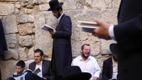 Judíos ortodoxos rezan mientras leen el libro de Eicha (Libro de las Lamentaciones) para conmemorar Tishá B'av, en el Muro de las Lamentaciones, en la Ciudad Vieja de Jerusalén.