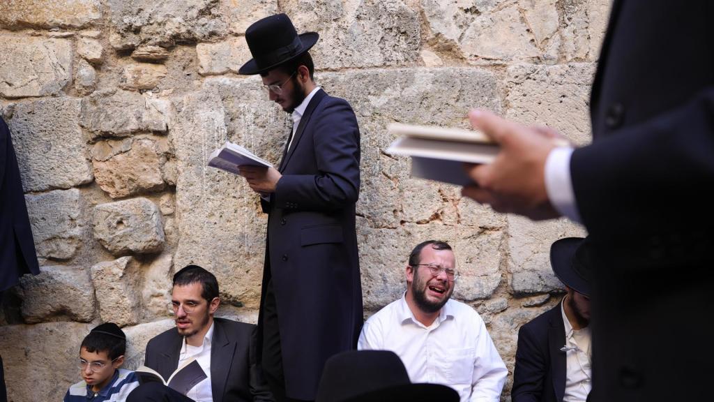 Judíos ortodoxos rezan mientras leen el libro de Eicha (Libro de las Lamentaciones) para conmemorar Tishá B'av, en el Muro de las Lamentaciones, en la Ciudad Vieja de Jerusalén.