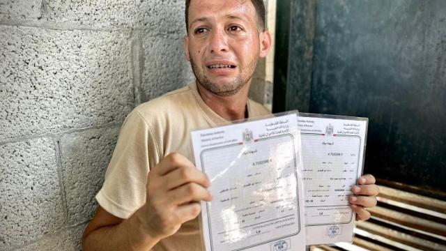 Mohammad Abu Al Qumsan sostiene los certificados de nacimiento de sus gemelos, quienes murieron en un ataque tres días después de su nacimiento.