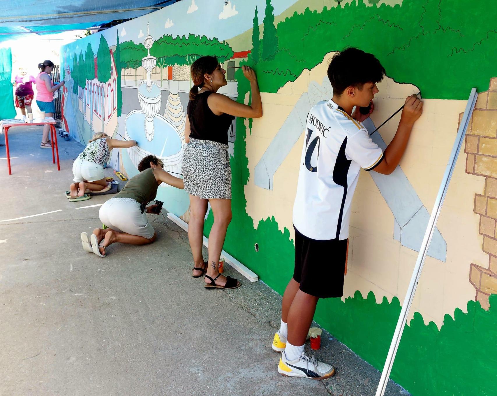 Niños y mayores pintando el mural en Peleas de Arriba