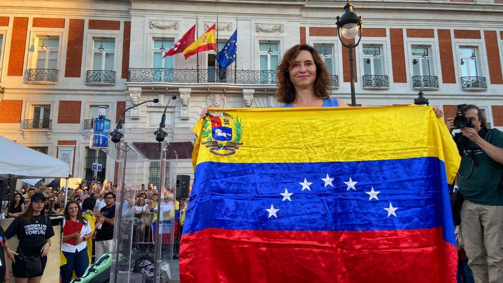 Isabel Díaz Ayuso porta la bandera de Venezuela, en la Puerta del Sol, este sábado.