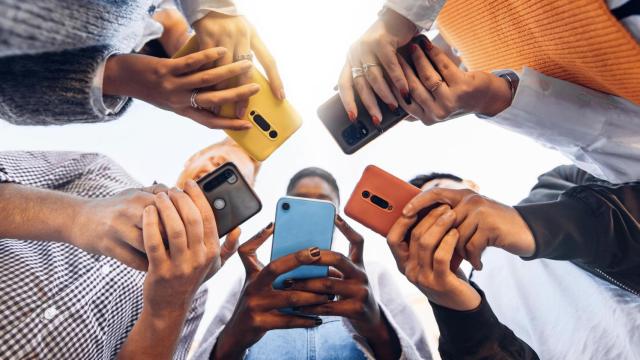 Grupo de jóvenes observando sus teléfonos móviles.