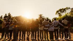 Vista trasera de un conjunto de personas abrazándose.