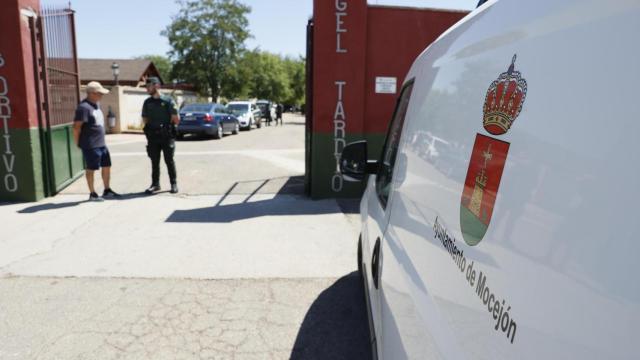 Un agente de la Guardia Civil habla con un vecino en la entrada al campo de fútbol de Mocejón (Toledo) donde un niño de 11 años ha muerto este domingo tras ser agredido con un objeto punzante.