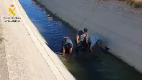 Agentes de la Guardia Civil buscan el arma homicida en una acequia de Mocejón.