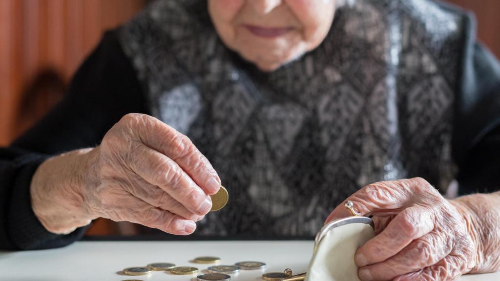 Una anciana contando dinero de su monedero.