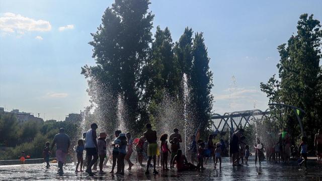 Un grupo de niños se refrescan en una fuente de Madrid Río durante una ola de calor en agosto.