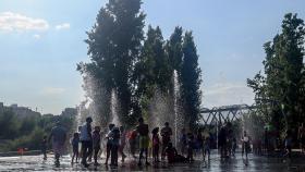 Un grupo de niños se refrescan en una fuente de Madrid Río durante una ola de calor en agosto.