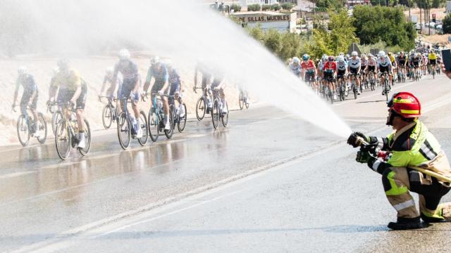 Un bombero esparce agua entre los ciclistas de La Vuelta 2024 para refrescarlos.