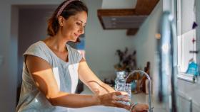 Una mujer coge agua del grifo para beber