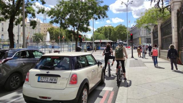 Vehículos y ciclistas en el Paseo de la Castellana con vistas a la Plaza de Cibeles.