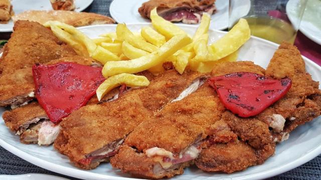 Un cachopo con patatas y pimientos.