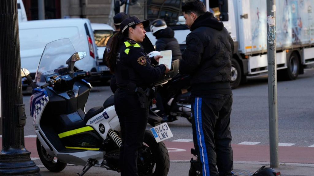 Una policía de la Guardia Urbana de Barcelona sanciona a un hombre por circular incorrectamente con su patinete eléctrico.