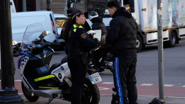 Una policía de la Guardia Urbana de Barcelona sanciona a un hombre por circular incorrectamente con su patinete.