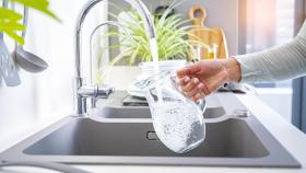 Una persona llenando una jarra de agua del grifo