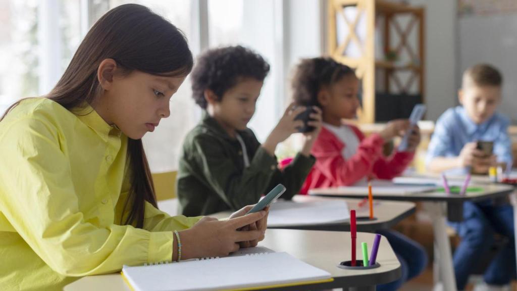 Niños en escuela de infantil con dispositivos electrónicos