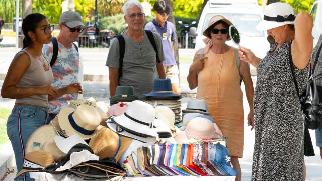 Un grupo de turistas compra gorros para protegerse del sol en Sevilla.