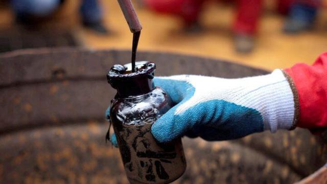 Un trabajador recoge una muestra de curdo en un pozo petrolífero.