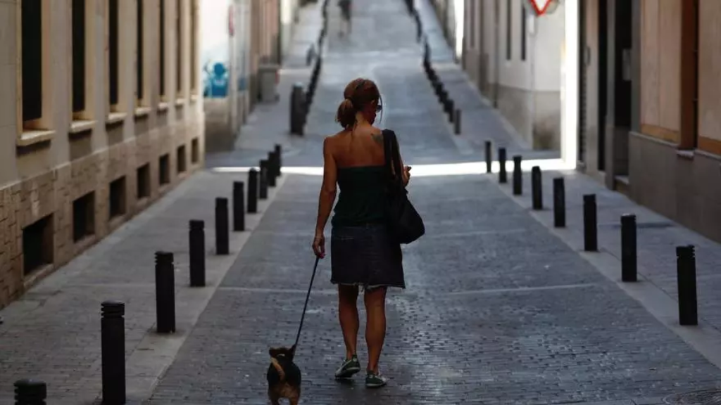 Una chica pasea a su perro por una calle del centro de Madrid.