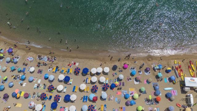 Numerosas personas disfrutan de un día de playa en la Costa Brava.