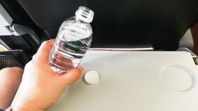 Una mujer sujeta una botella de agua en un avión.