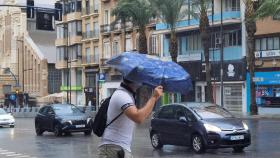 Un peatón cruzando Alfonso el Sabio bajo la tormenta de este miércoles en Alicante.