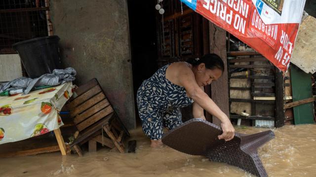 Una mujer intenta proteger sus enseres de las inundaciones provocadas por la tormenta tropical Yagi.