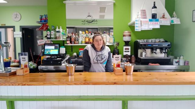 La joven sonríe detrás de la barra de su bar, ubicado dentro de la Casa da Cultura de Alfoz (Galicia).