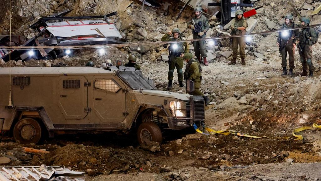 Miembros del ejército israelí se mantienen junto a un vehículo militar mientras continúa una incursión israelí en Jenin, en Cisjordania.