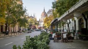 Calle de Budapest con cafeterías y vistas al Parlamento.