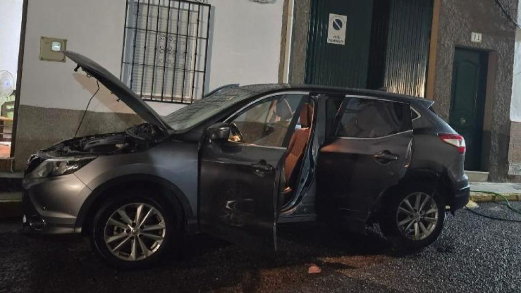 El guardia civil atacado junto al estado en el que quedó su coche particular tras ser quemado en Granada.