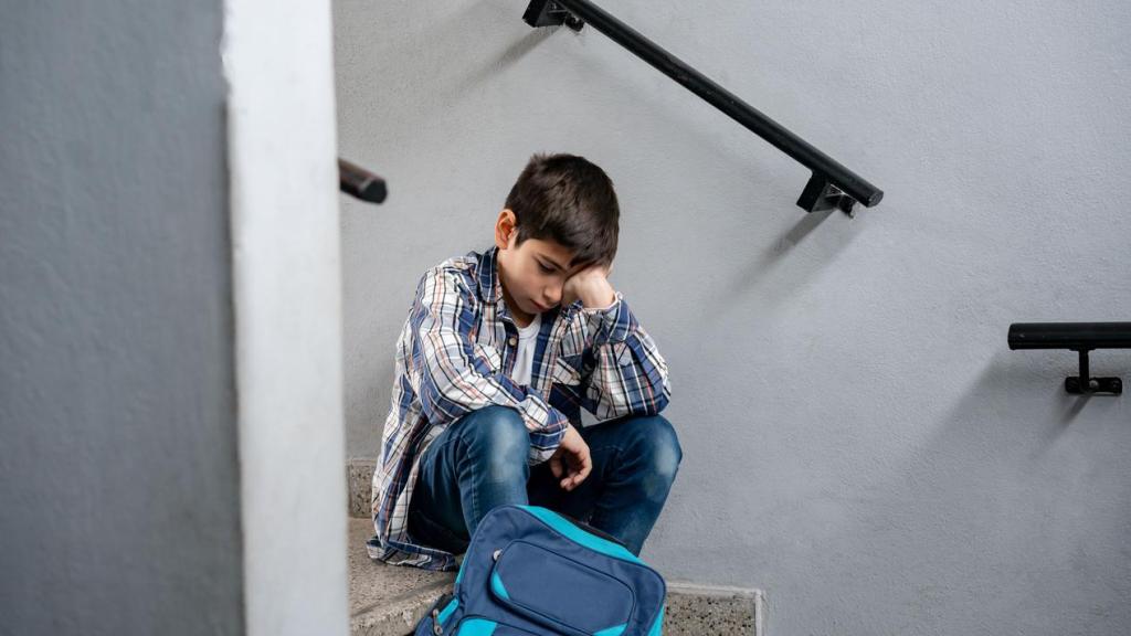 Niño triste y solo sentado en las escaleras de su escuela.