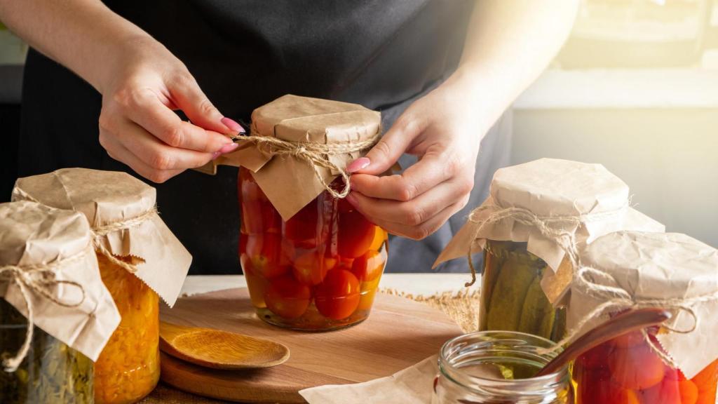 Una persona con un bote de tomates en conserva