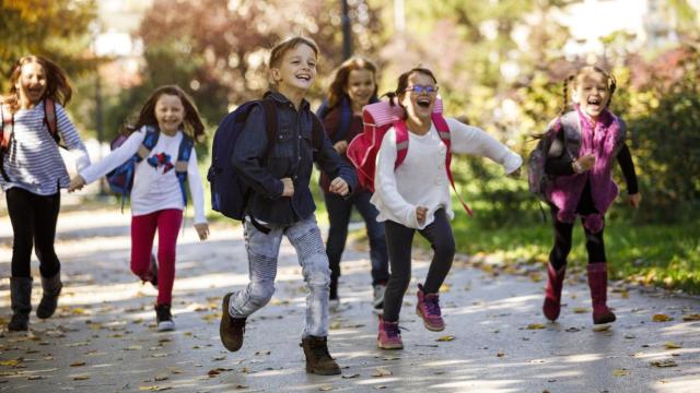 Niños corriendo entusiasmados hacia al colegio.