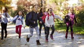 Niños corriendo entusiasmados hacia al colegio.