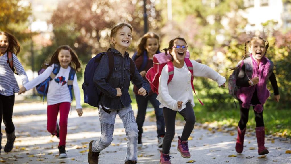 Niños corriendo entusiasmados hacia al colegio.