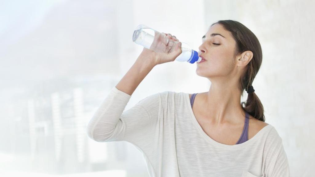 Mujer bebiendo agua de una botella.